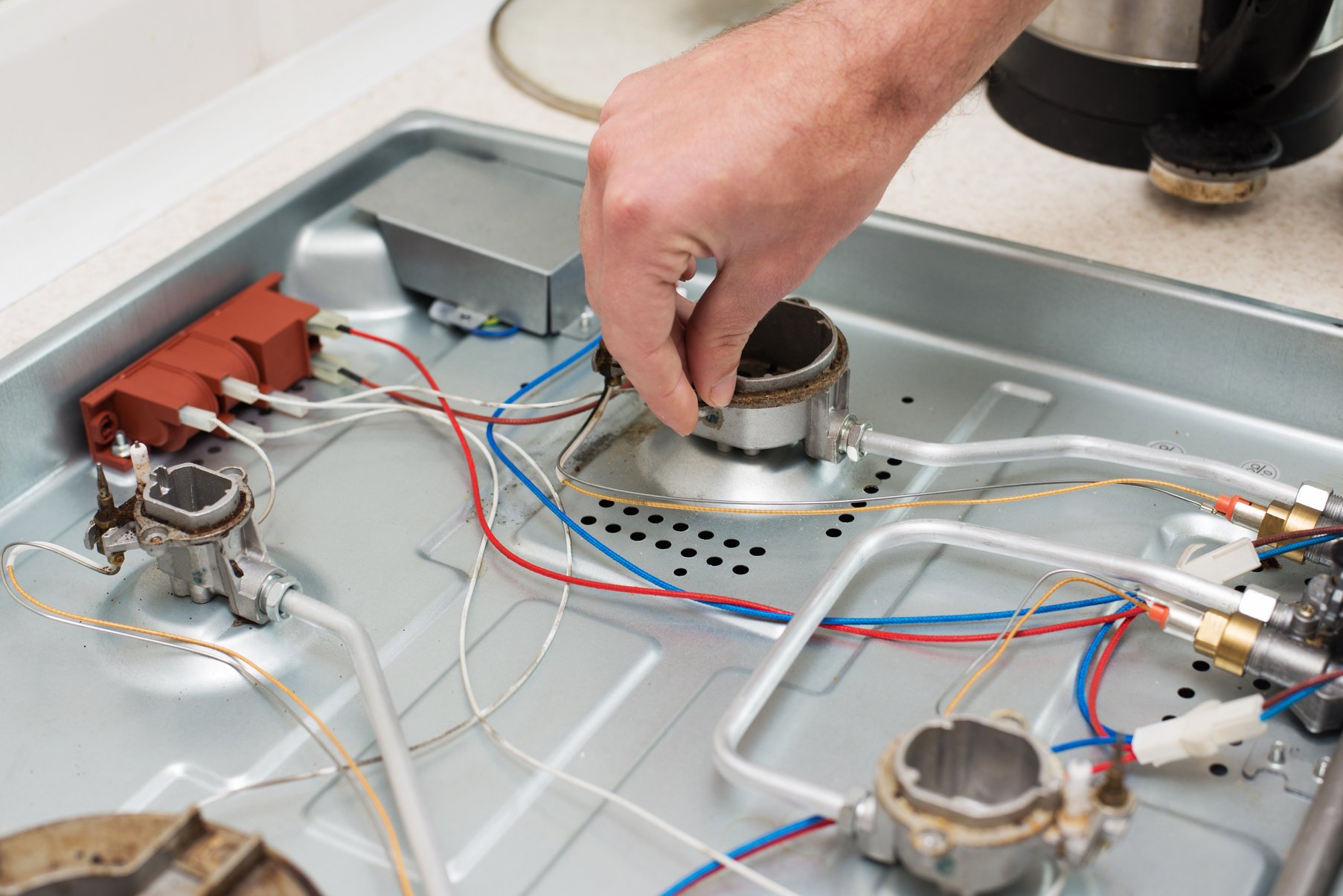 Man Hand Repairs Hotplate of Gas Panel