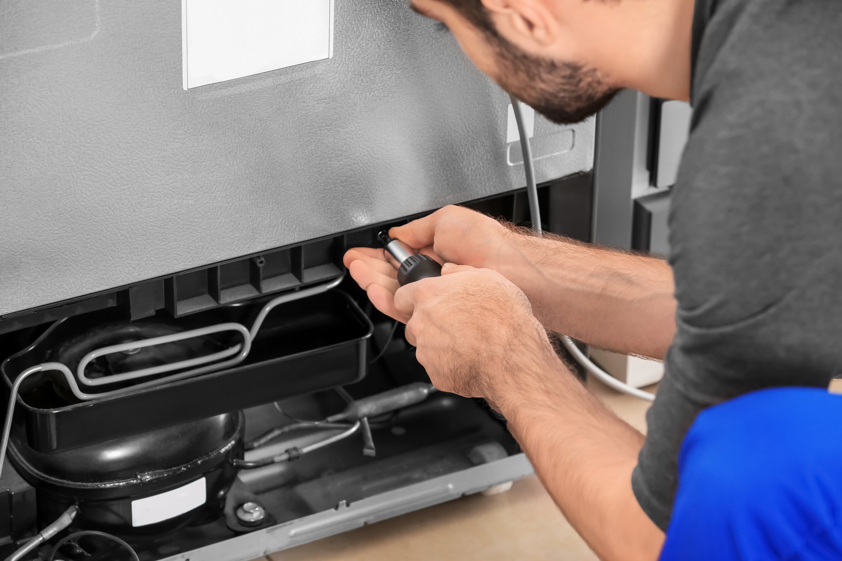 Male Technician Repairing Refrigerator Indoors